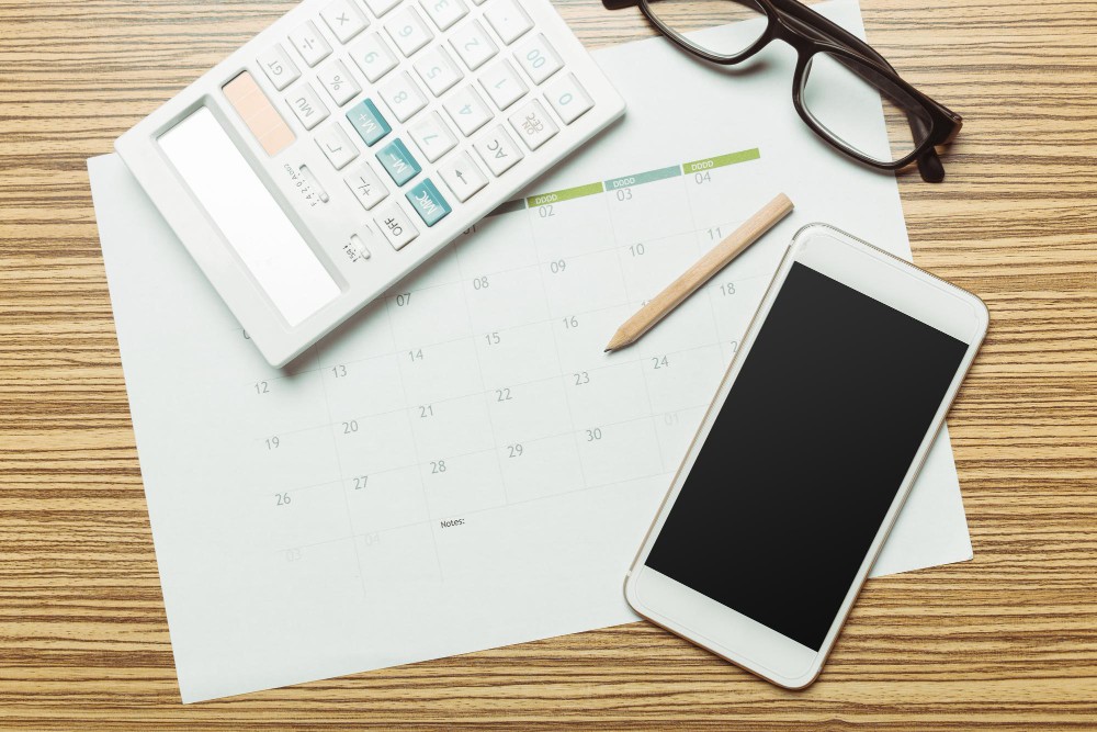 Na imagem á ferramentas utilizadas para saber como calcular os dias trabalhados, como uma calculadora e um calendário.